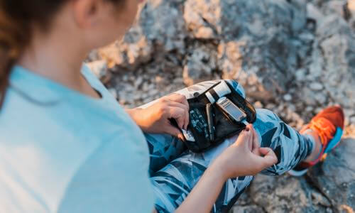 Young woman sitting outside on a rock testing her blood sugar with a BGM