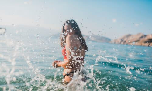 Woman wading in ocean wearing water-resistant blood glucose monitoring smartwatch
