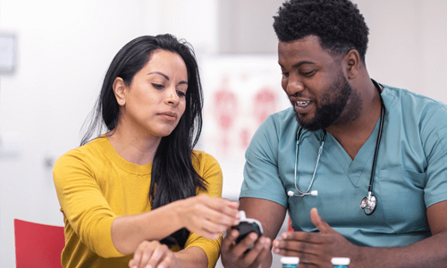 Male health care professional showing female patient a glucose meter